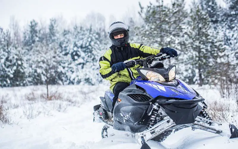 Man driving snowmobile in CT through the snow. 