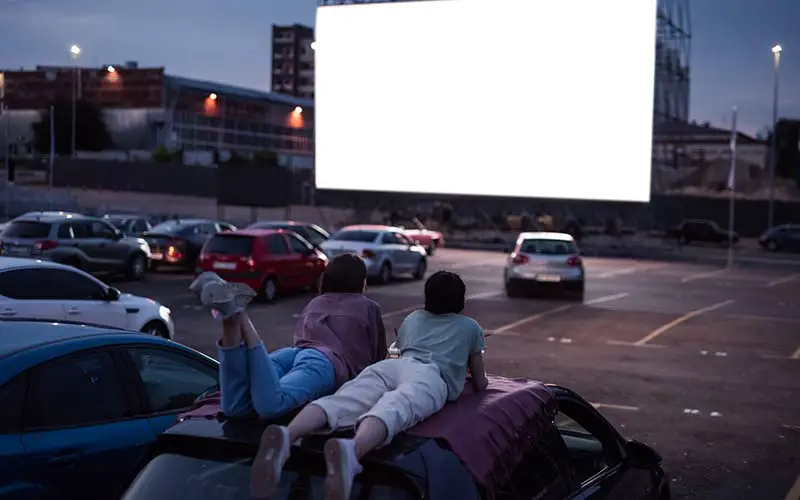 A couple of kids watching a movie at a drive in movie theater in CT.